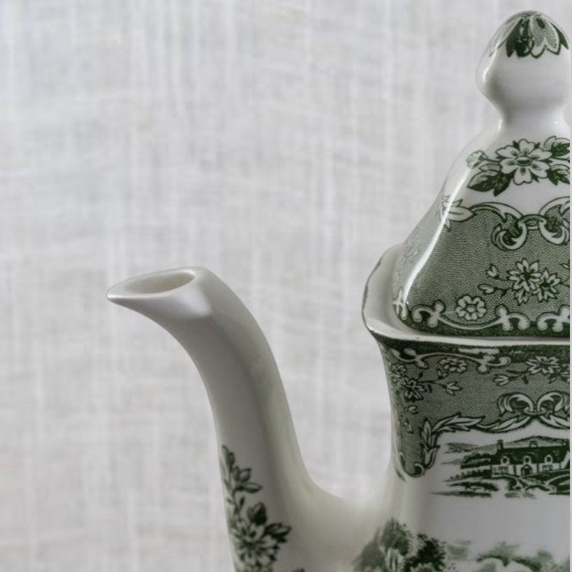 Close-up of vintage Grindley coffee pot spout and lid.. Made from English earthenware with a green transferware Tudor cottage pattern.