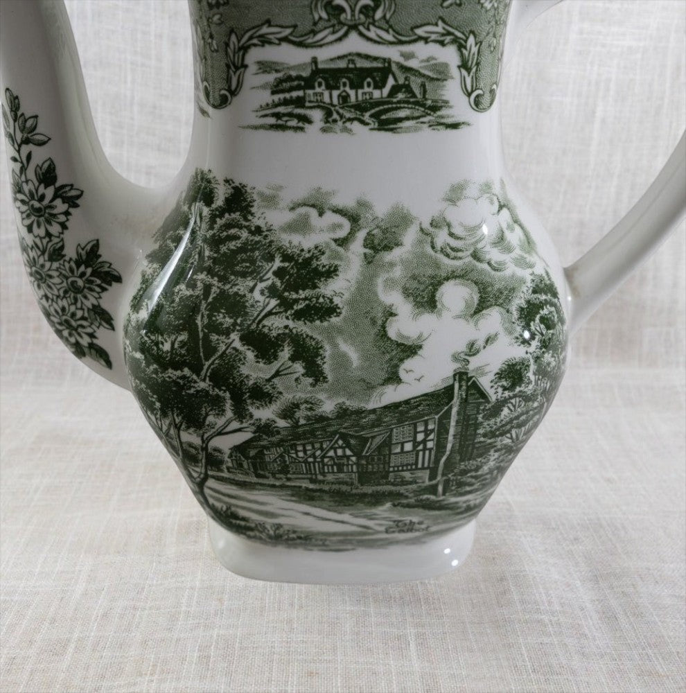 Close-up of vintage Grindley coffee pot body ft. a green Tudor cottage transferware pattern.