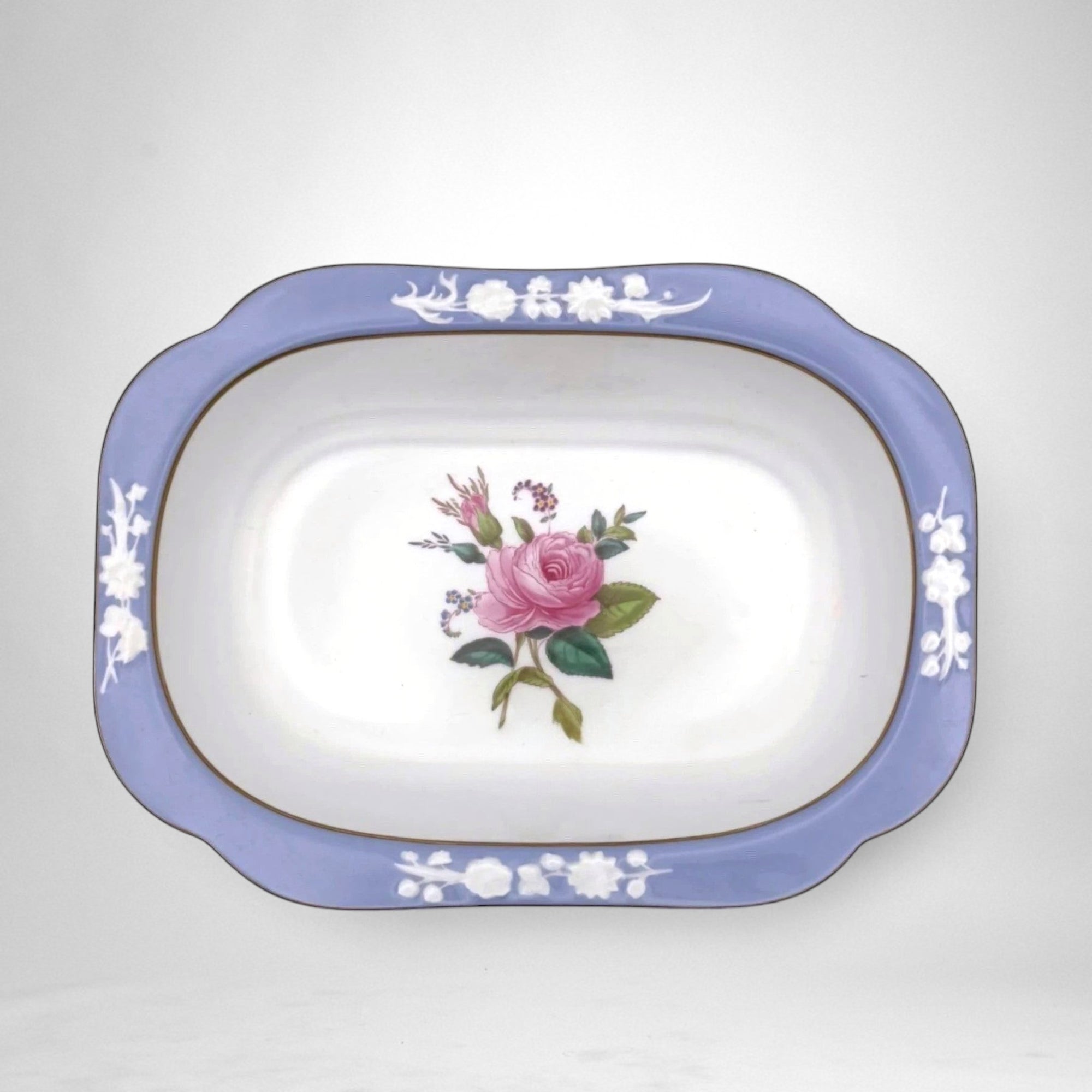 The Brooklyn Teacup oval serving bowl featuring a blue rim with white floral relief and a central pink rose motif.