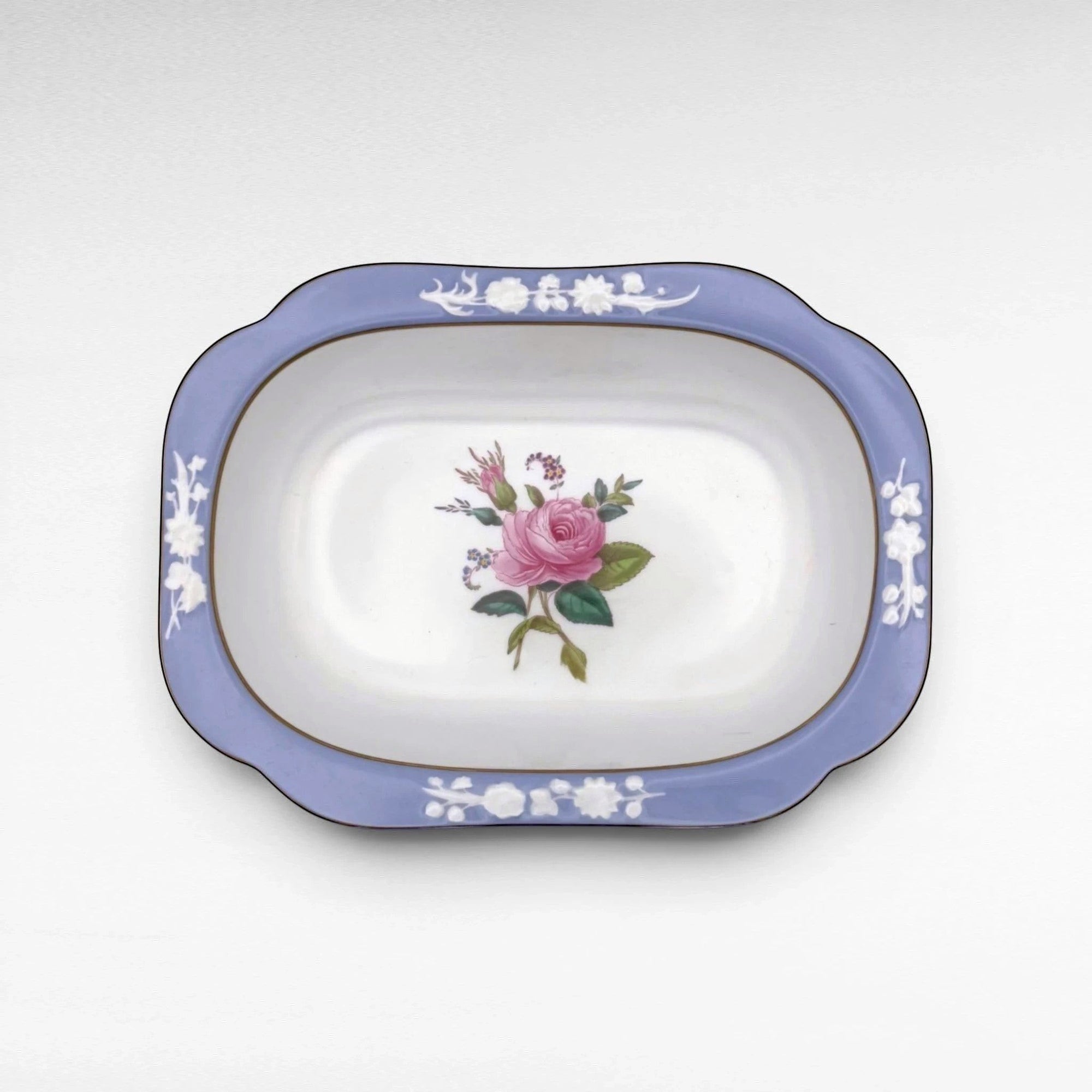 The Brooklyn Teacup oval serving bowl featuring a blue rim with white floral relief and a central pink rose motif.