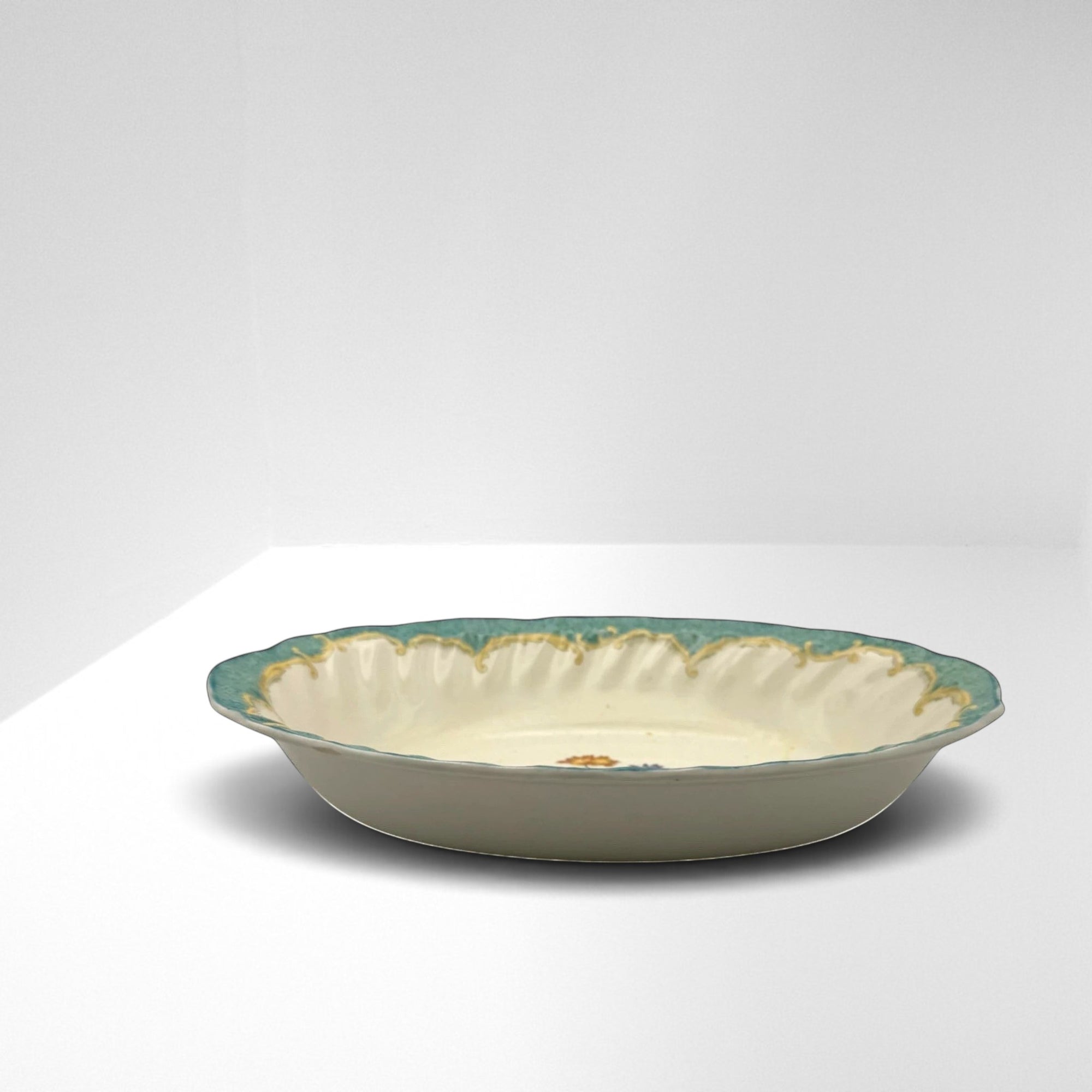 The Brooklyn Teacup oval serving bowl with a scalloped teal rim and delicate floral pattern on cream ceramic.