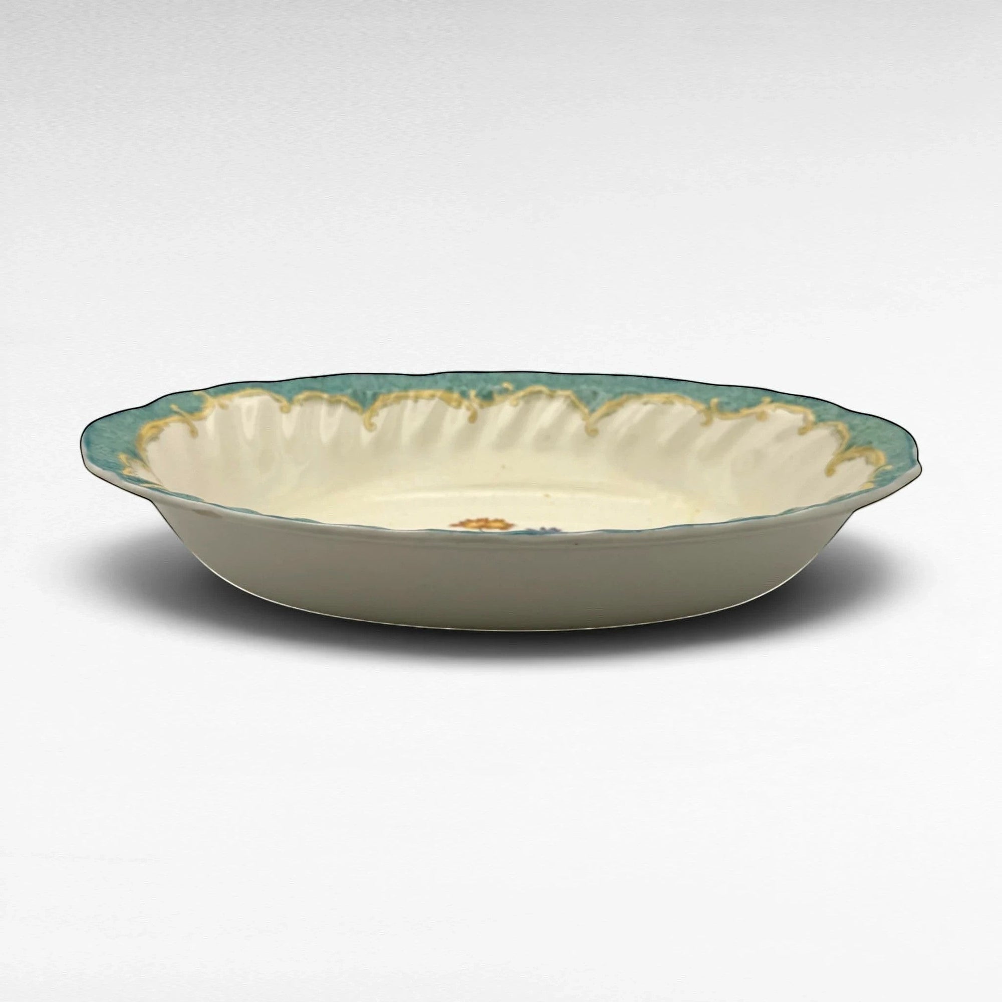 The Brooklyn Teacup oval serving bowl with a scalloped teal rim and delicate floral pattern on cream ceramic.