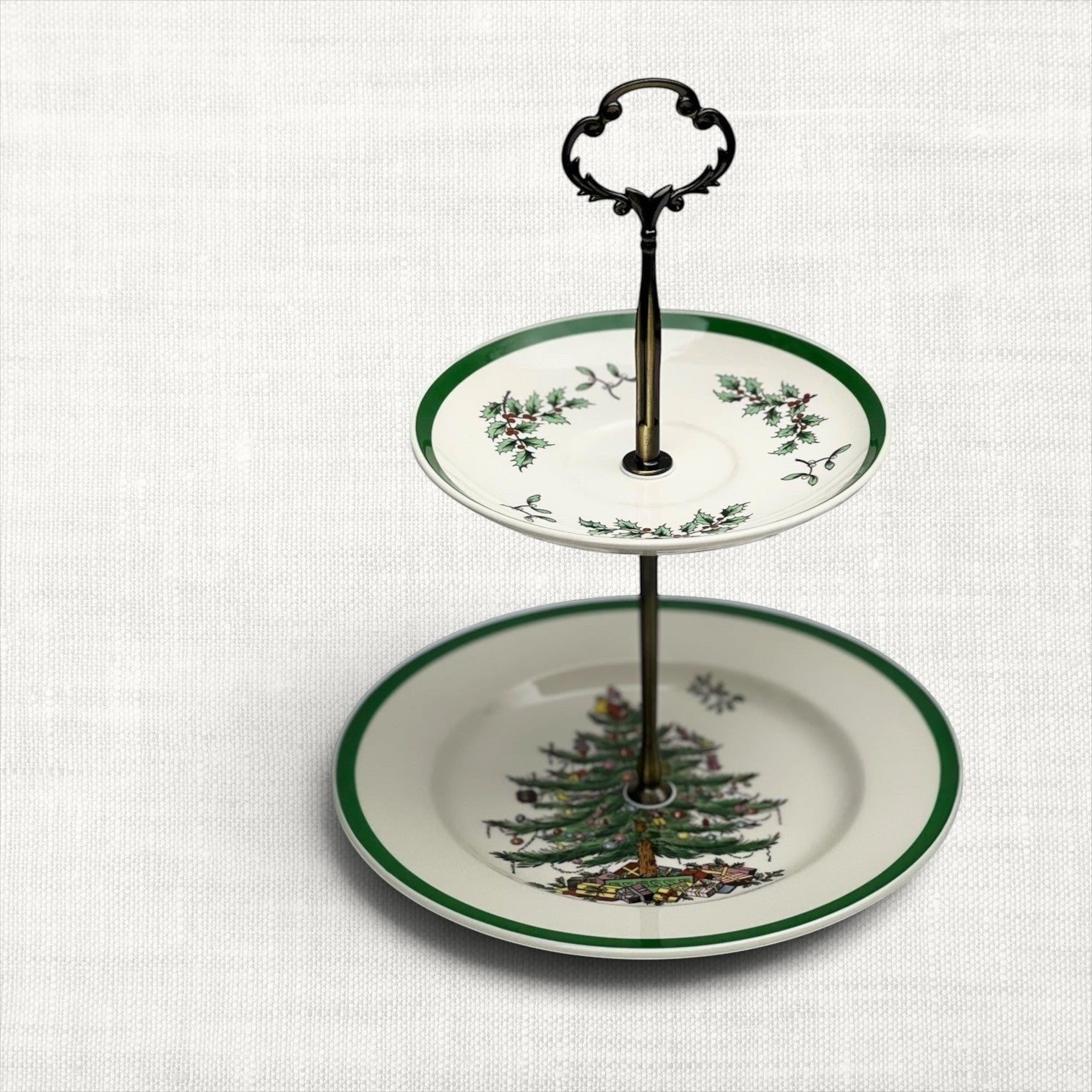 Spode Christmas Tree two-tiered serving tray with festive holiday tree and green border accent. Paired with bronze, ribbon-shaped hardware.