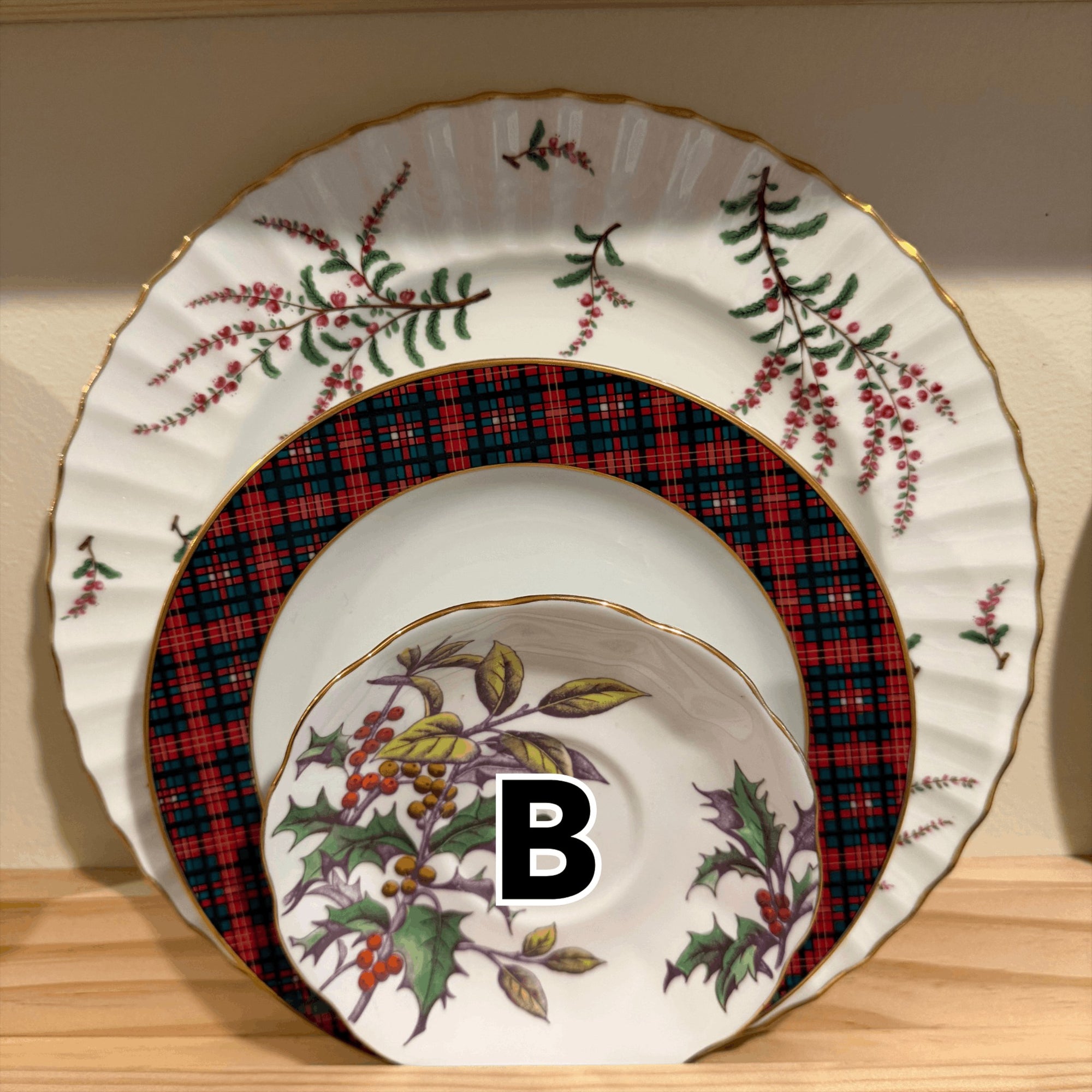 The Brooklyn Teacup vintage Christmas 3-tier tray plates featuring holly, berry, and red plaid patterns with gold rims.