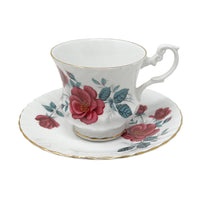 Deep pink/ruby red roses with green leaves on white bone china teacup and saucer.